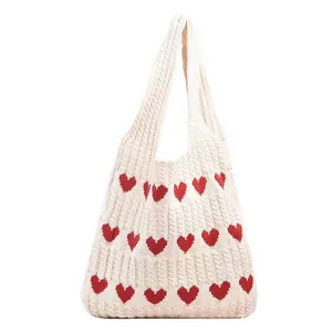 Detail of knit handbag showing cream yarn texture and red heart crochet patterns