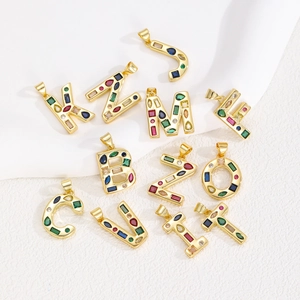 Colorful zircon-inlaid gold alphabet pendants set on a white textured background