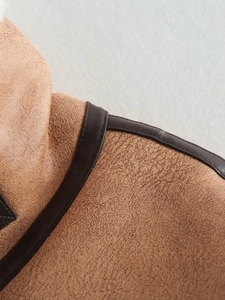 Detailed view of shoulder stitching and faux suede texture on a brown vest