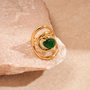 Macro detail of a golden spiral ring featuring a faceted emerald green zircon center
