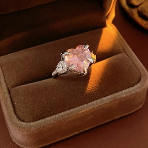 Detailed shot of a heart-shaped pink zircon ring nestled in a brown velvet jewelry box