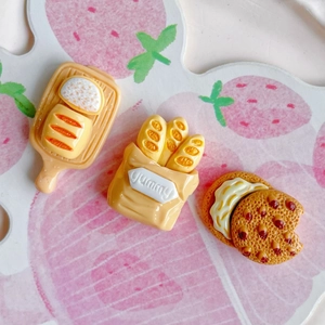 Macro view of 3-piece miniature resin food set including bread and cookies on strawberry mat