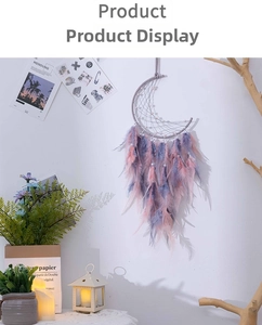 Detail of crescent moon dreamcatcher with pink and purple feathers on a white wall