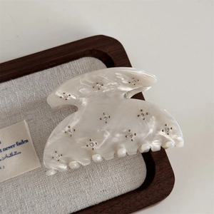 Close-up of pearlescent acetate hair claw clip with rhinestones on a wooden tray