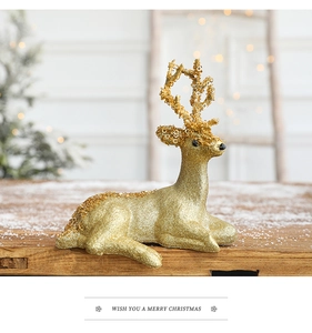Close-up of champagne gold glitter reindeer statue on a snowy rustic wooden table