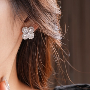 Gros plan sur les puces d'oreilles trèfle en argent avec oxydes de zirconium sur modèle