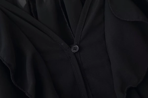 Close-up of black V-neck shirt featuring elegant ruffle trim and single button detail