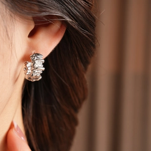 Close-up of irregular textured silver hoop earring worn on a model ear lobe