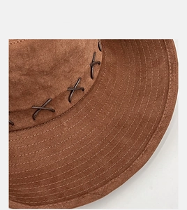 Close-up detail of dark brown suede cowboy hat with decorative cross-stitch sewing