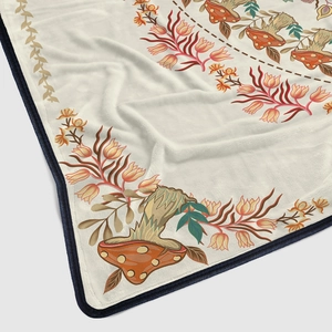 Close-up of flannel blanket with hand-drawn red mushroom and yellow floral patterns