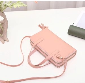 Close-up of pink crossbody bag with dual-layer zippers and elegant fringe tassel detail