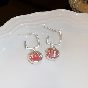 Macro shot of silver flower earrings with pink enamel pendant and letter M detail