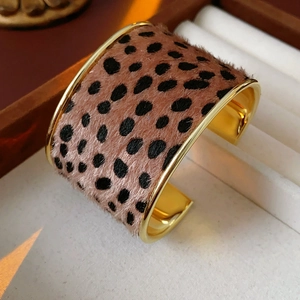 Detail of wide leopard print bangle with a golden metal inner lining and flocking texture