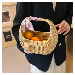 Detail of woven straw basket bag with a stylish pink patterned silk scarf on the handle