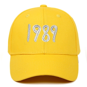 Detailed close-up of silver 1989 embroidery on the front of a bright yellow cotton baseball cap