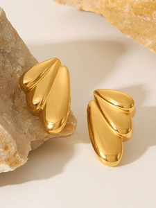 Detailed view of gold wing-shaped earrings on stone base with smooth 18k finish