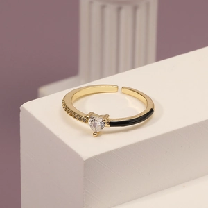 Detailed close-up of golden adjustable heart ring with black enamel and zircon stones
