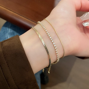 Three-piece gold snake chain bracelet set with zircon accents worn on female wrist