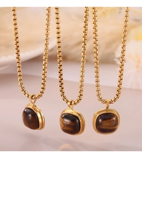Macro shot of three gold necklaces featuring square brown tiger eye stone pendants