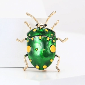 Macro shot of green enamel beetle brooch with yellow spots and golden metallic legs