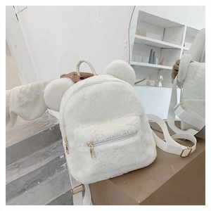 Detailed macro view of a white plush backpack with cute bear ear design and golden zippers