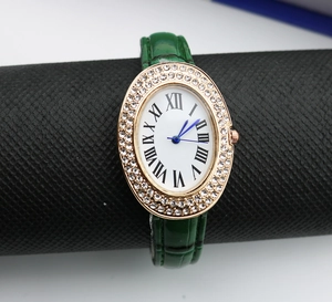 Macro detail of the rose gold rhinestone bezel and green leather strap on the oval watch