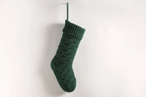 Close-up of dark green knitted Christmas stocking featuring a unique fish scale texture