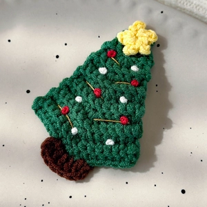 Detailed view of a handmade crochet Christmas tree hair clip with red and white accents