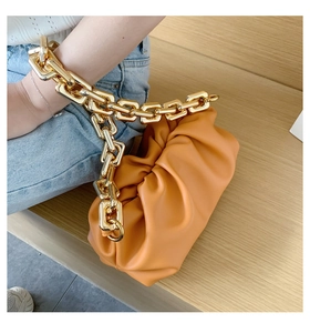 Detailed view of yellow cloud pouch with thick gold chain strap and soft leather pleats