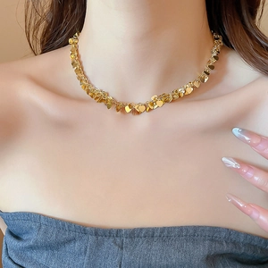 Dettaglio macro di un girocollo a paillettes a forma di cuore dorato con trama