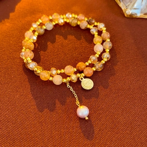 Detail of 2-piece natural orange stone bracelet set with gold charms and pearls
