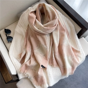 Detail of pink and white plaid scarf with fringe and Cashmere label on a white sweater