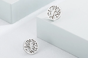 Detailed view of silver tree of life earrings on a minimalist geometric display stand