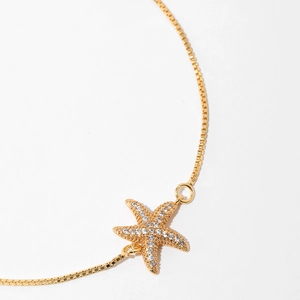 Macro view of gold-plated starfish pendant with sparkling zircon micro-pave details