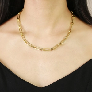 Close-up of a gold rectangular paperclip link chain necklace worn on a woman's neck