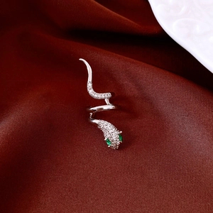 Macro view of silver snake jewelry featuring clear zircon pave and green emerald eyes