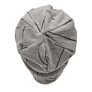 Close-up of light gray waffle knit texture and black linear patterns on a beanie hat