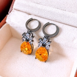 Detail of vintage pear-cut orange zircon drop earrings with black gold finish in a gift box