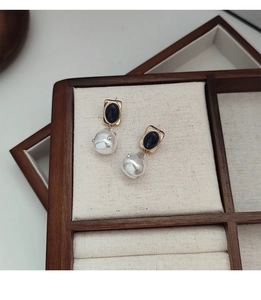 Dettaglio macro di orecchini vintage con pietre blu e perle barocche su vassoio