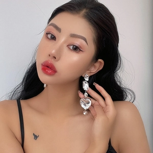 Detailed view of silver long geometric heart earrings with sparkling crystals on model