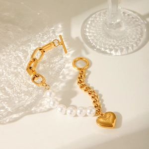 Detailed view of a gold heart pendant bracelet with white pearls and OT toggle clasp