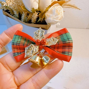 Close-up of a Christmas plaid bow hair clip with golden bells and red holly berries