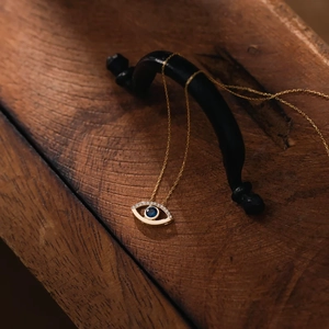 Golden Evil Eye necklace with blue and white stones on a vintage metal hanger