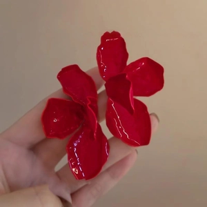 Detail of red floral petal earrings with a glossy finish and layered oversized design
