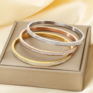 Dettaglio di tre bracciali ovali con zirconi cubici nei colori oro, oro rosa e argento