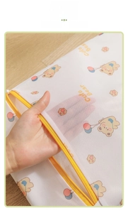 Close-up of fine mesh laundry bag featuring a cartoon bear print and yellow zipper
