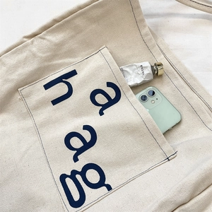 Detail of canvas tote bag showing navy blue haag print and smartphone in pocket