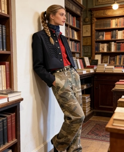 Detailed view of dark blue military cropped jacket styled with red shirt and camo pants