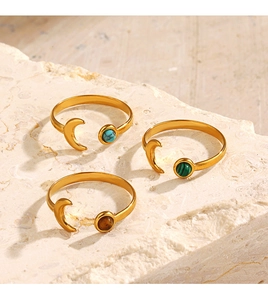 Detailed shot of moon-shaped gold rings featuring turquoise, malachite, and tiger eye stones