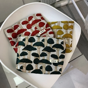 Detail view of mushroom jacquard fabric travel cosmetic bags in red, yellow and green